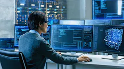 man at work station in control room reviewing multiple displays with analytics data and modeling