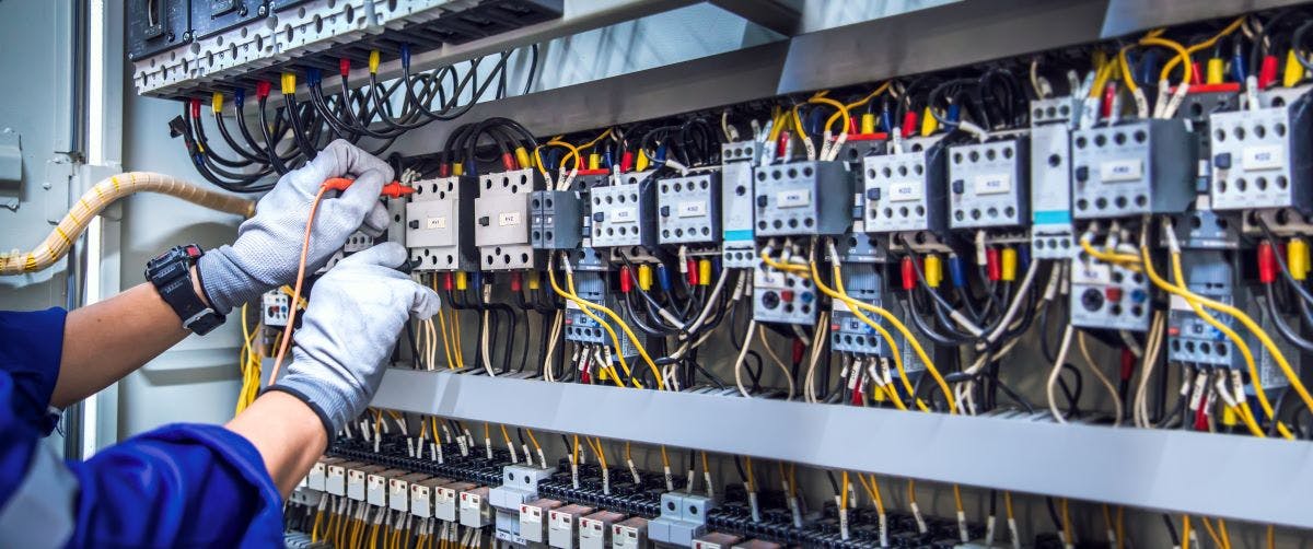 Electricity and electrical maintenance service, Engineer hand holding AC voltmeter checking electric current voltage at circuit breaker terminal and cable wiring main power distribution board.