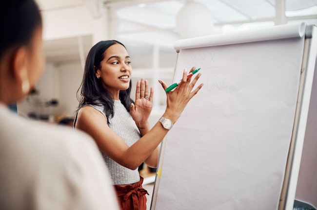 Woman, mentor and whiteboard in office for training, teaching and learning for skill or career development