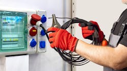 Electrician connects a high-power cable to an industrial socket panel, performing setup tasks related to electrical installation and temporary power distribution systems. Electrician connects a high-power cable to an industrial socket panel, performing setup tasks related to electrical installation and temporary power distribution systems.
