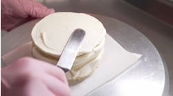 Female professional hands levels cream on baked sponge cake using metallic pastry scraper Female professional hands levels cream on baked sponge cake using metallic pastry scraper