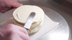 Female professional hands levels cream on baked sponge cake using metallic pastry scraper Female professional hands levels cream on baked sponge cake using metallic pastry scraper