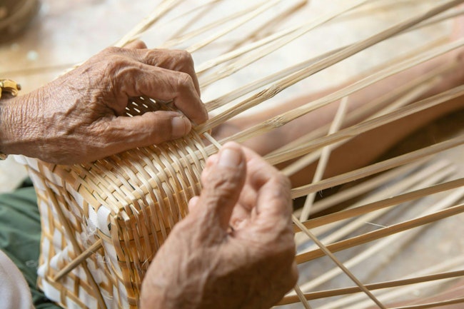 Senior man hands manually weaving bamboo.