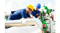 Two petrochemical workers inspecting pressure valves on a fuel tank Two petrochemical workers inspecting pressure valves on a fuel tank
