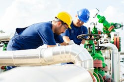 Two petrochemical workers inspecting pressure valves on a fuel tank Two petrochemical workers inspecting pressure valves on a fuel tank