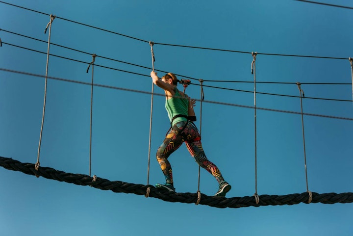 Skilled adult woman racing through the difficult course in the adventure park with ease