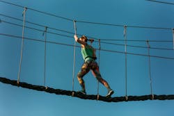 Skilled adult woman racing through the difficult course in the adventure park with ease Skilled adult woman racing through the difficult course in the adventure park with ease