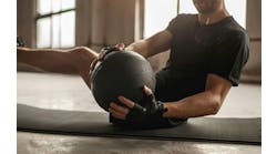 Side view of crop unrecognizable athletic male doing side twist exercise with medicine ball during intense functional training in gym Side view of crop unrecognizable athletic male doing side twist exercise with medicine ball during intense functional training in gym