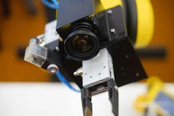 A robot in a factory equipped with a machine vision camera. A robot in a factory equipped with a machine vision camera.