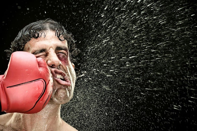 boxer man takes a punch in the face isolated on black.
