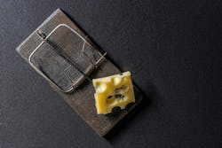 Wooden mousetrap with a piece of yellow cheese on a dark background, close up, top view. Wooden mousetrap with a piece of yellow cheese on a dark background, close up, top view.