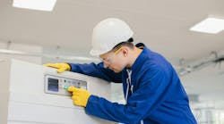 Industrial technician operating control panel, pushing button, wearing safety glasses, gloves, and helmet Industrial technician operating control panel, pushing button, wearing safety glasses, gloves, and helmet