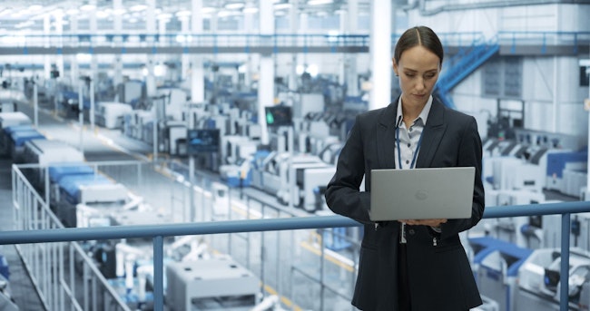Electronics Manufacturing Technician Working on a Laptop Computer at a Factory Space. Female Specialist Developing, Maintaining, Upgrading Programs for Machine Production and Assembly