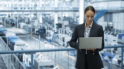 Electronics Manufacturing Technician Working on a Laptop Computer at a Factory Space. Female Specialist Developing, Maintaining, Upgrading Programs for Machine Production and Assembly Electronics Manufacturing Technician Working on a Laptop Computer at a Factory Space. Female Specialist Developing, Maintaining, Upgrading Programs for Machine Production and Assembly