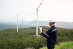 Engineer Monitoring Wind Turbine with Tablet: Technology and Efficiency in Renewable Energy. Business and Environmental Responsibility Engineer Monitoring Wind Turbine with Tablet: Technology and Efficiency in Renewable Energy. Business and Environmental Responsibility