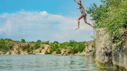Woman in swimsuit jumps off cliff into lake Woman in swimsuit jumps off cliff into lake