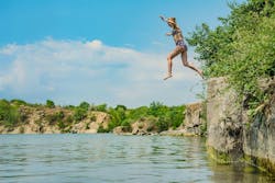 Woman in swimsuit jumps off cliff into lake Woman in swimsuit jumps off cliff into lake