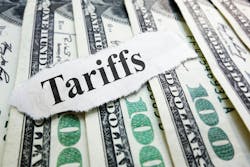 The word Tariffs typed on a scrap of paper laid atop several $100 bills The word Tariffs typed on a scrap of paper laid atop several $100 bills