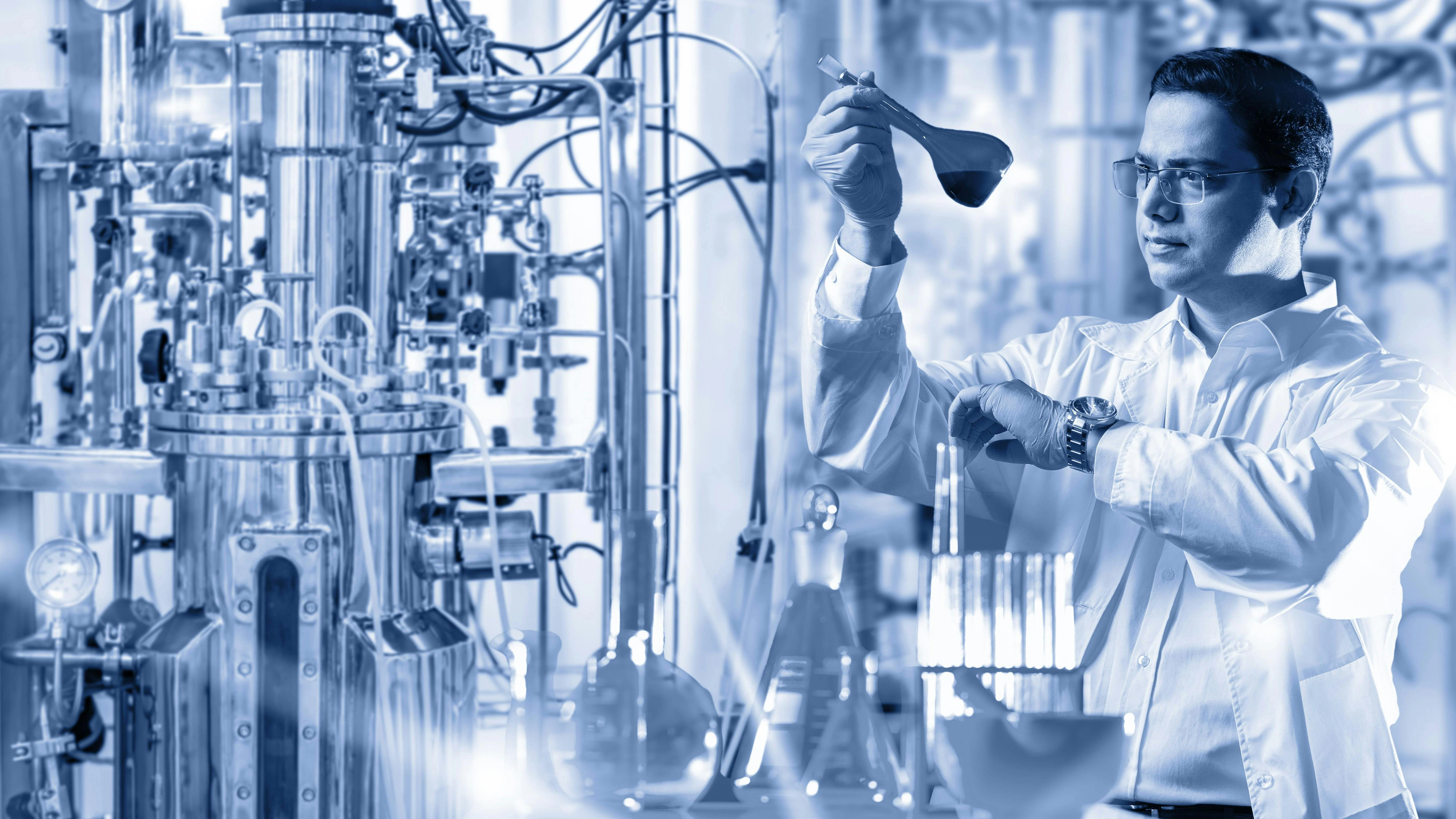 Black and white image of a scientist looking at a test tube in a laboratory