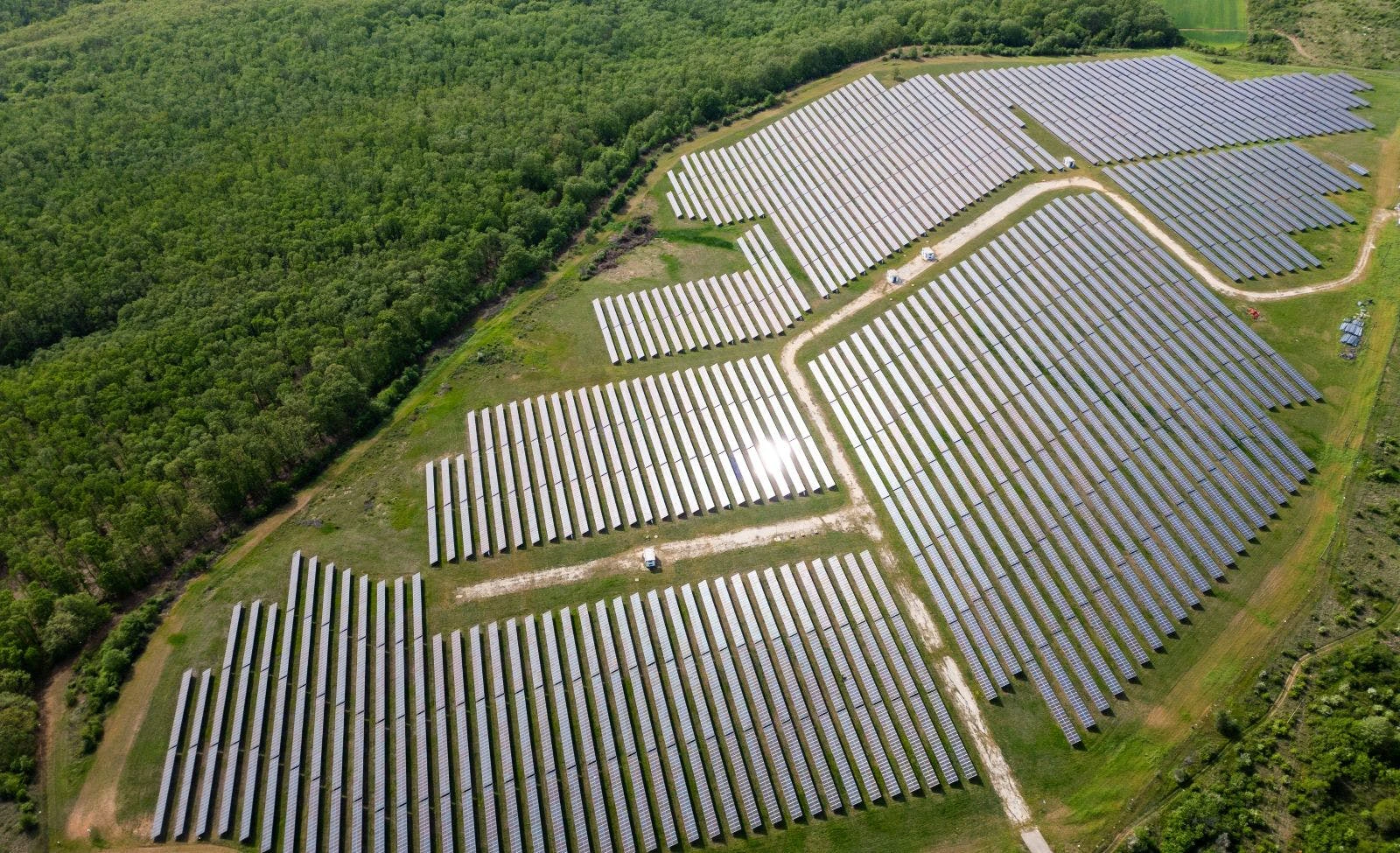 Drone view of a solar power station next to a forest during summer.