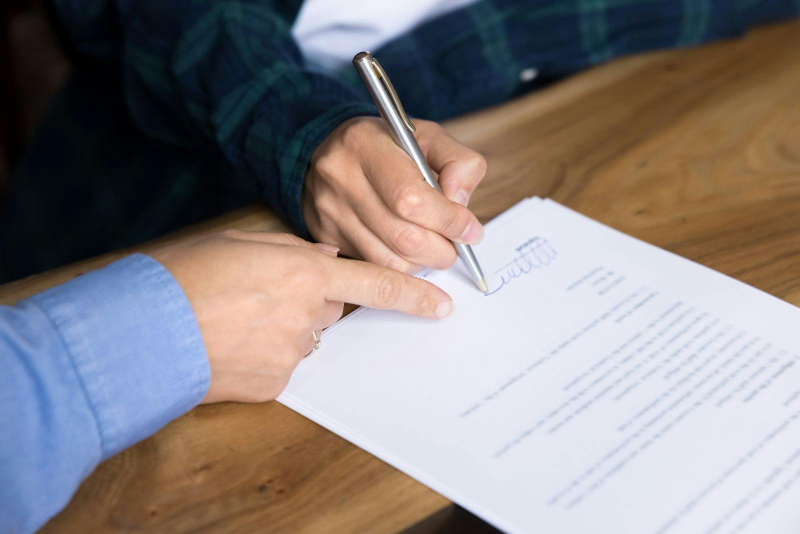 Close up, two unrecognizable businesswomen, customer and sales manager sit at desk, agent and client making commercial deal in moment of signing formal document,