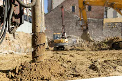 Industrial drilling rig auger creating a new building foundation at a development site with heavy machinery and excavated earth in an urban construction area Industrial drilling rig auger creating a new building foundation at a development site with heavy machinery and excavated earth in an urban construction area