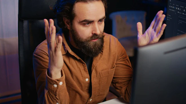 Disappointed computer scientist puzzled after being unable to remove all bugs while coding on workstation desktop.
