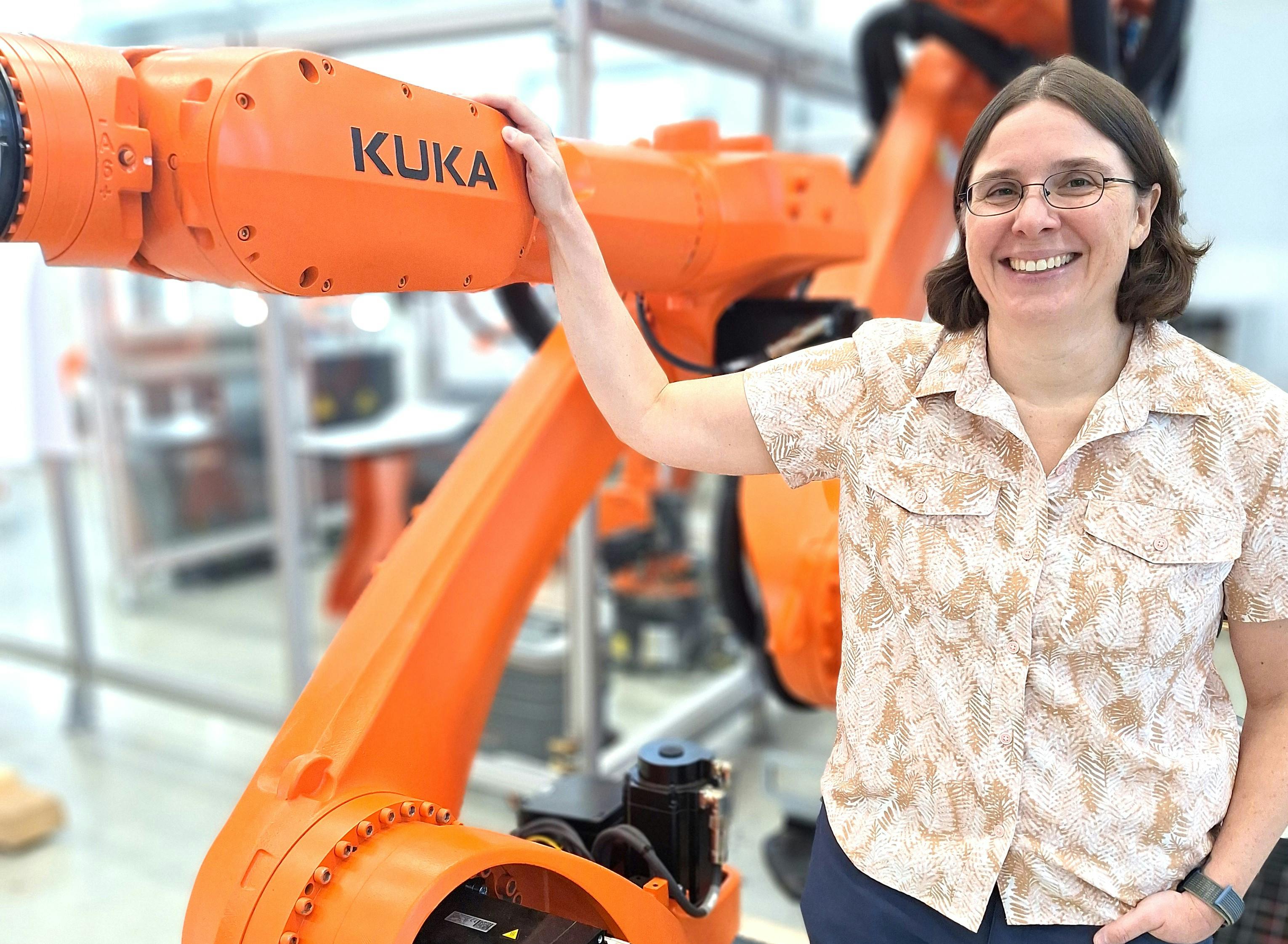 Melonee Wise, chief software and AI product officer at Kuka, standing next to a Kuka robotic arm.