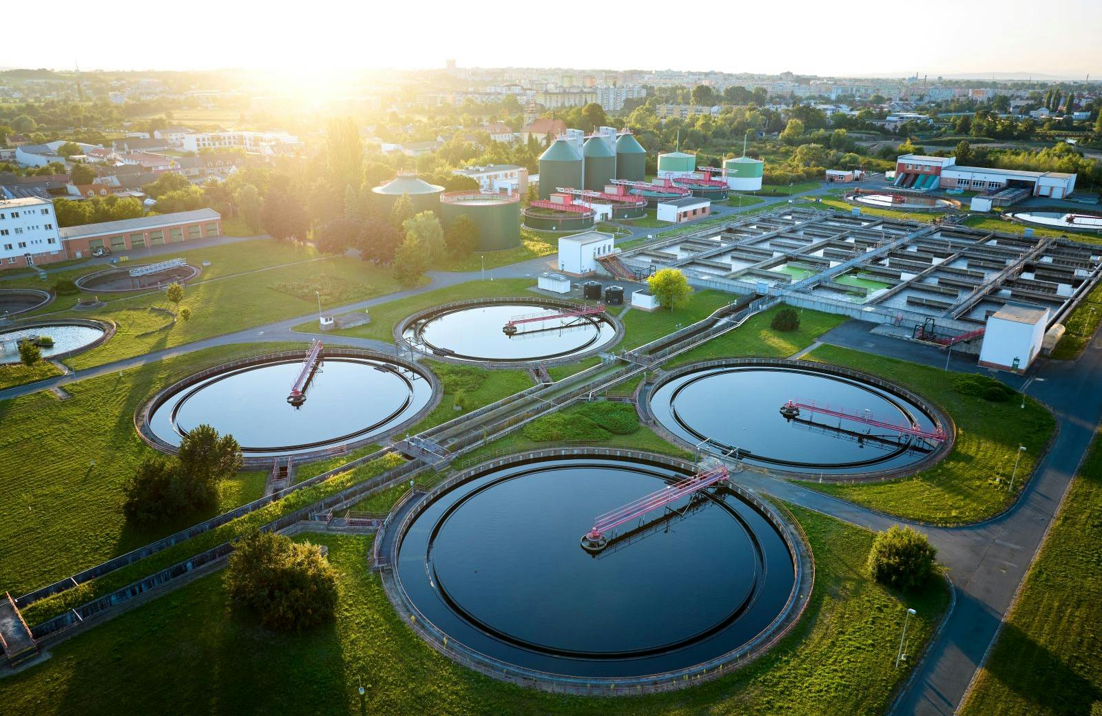 Aerial view of wastewater treatment plant at sunrise, ideal for illustrating sustainable water management, environmental engineering, and modern infrastructure in urban planning contexts.