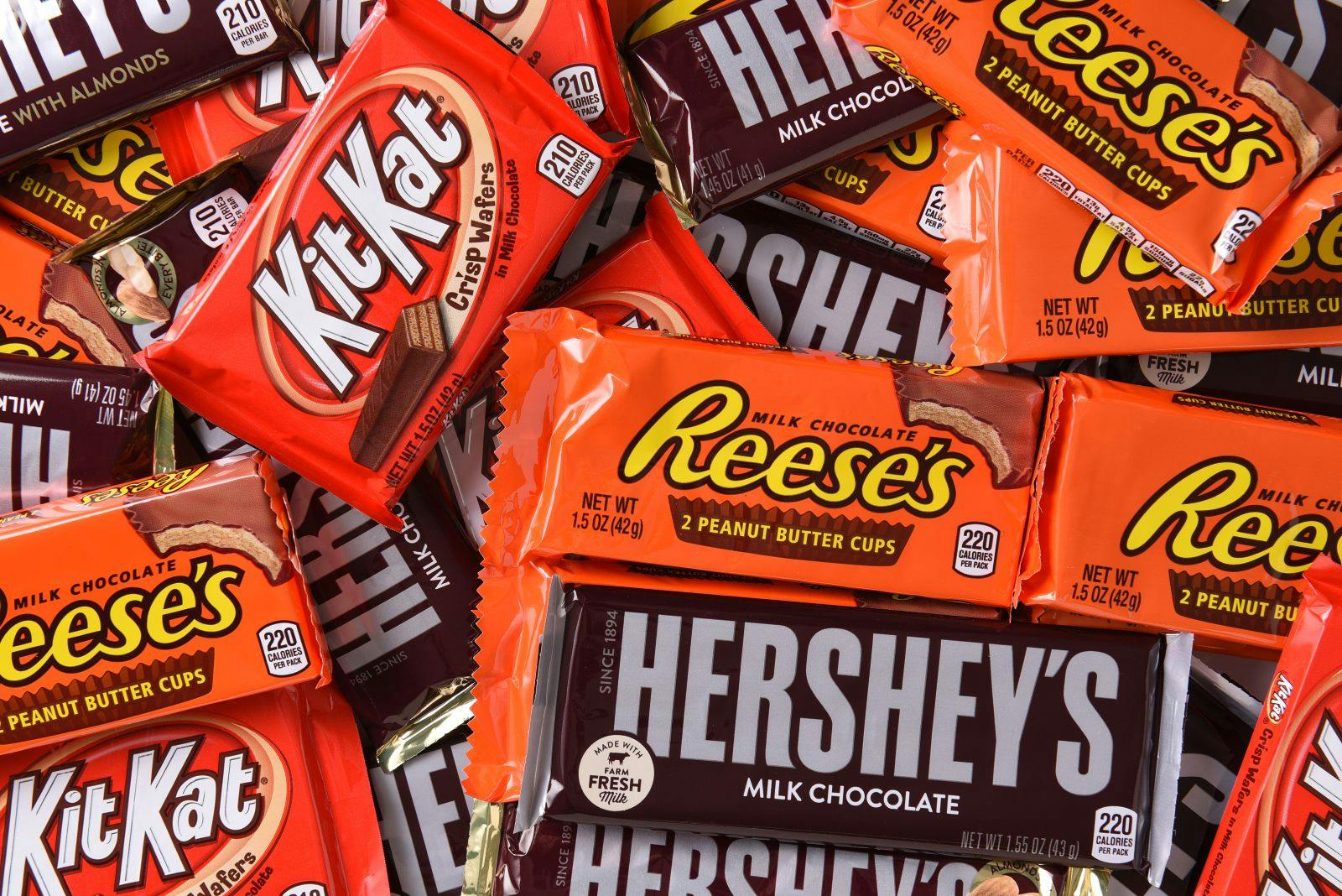 A close-up shot of a collection of Hershey's milk chocolate bars, Reese's cups and Kit Kat bars.