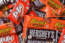 A close-up shot of a collection of Hershey's milk chocolate bars, Reese's cups and Kit Kat bars.