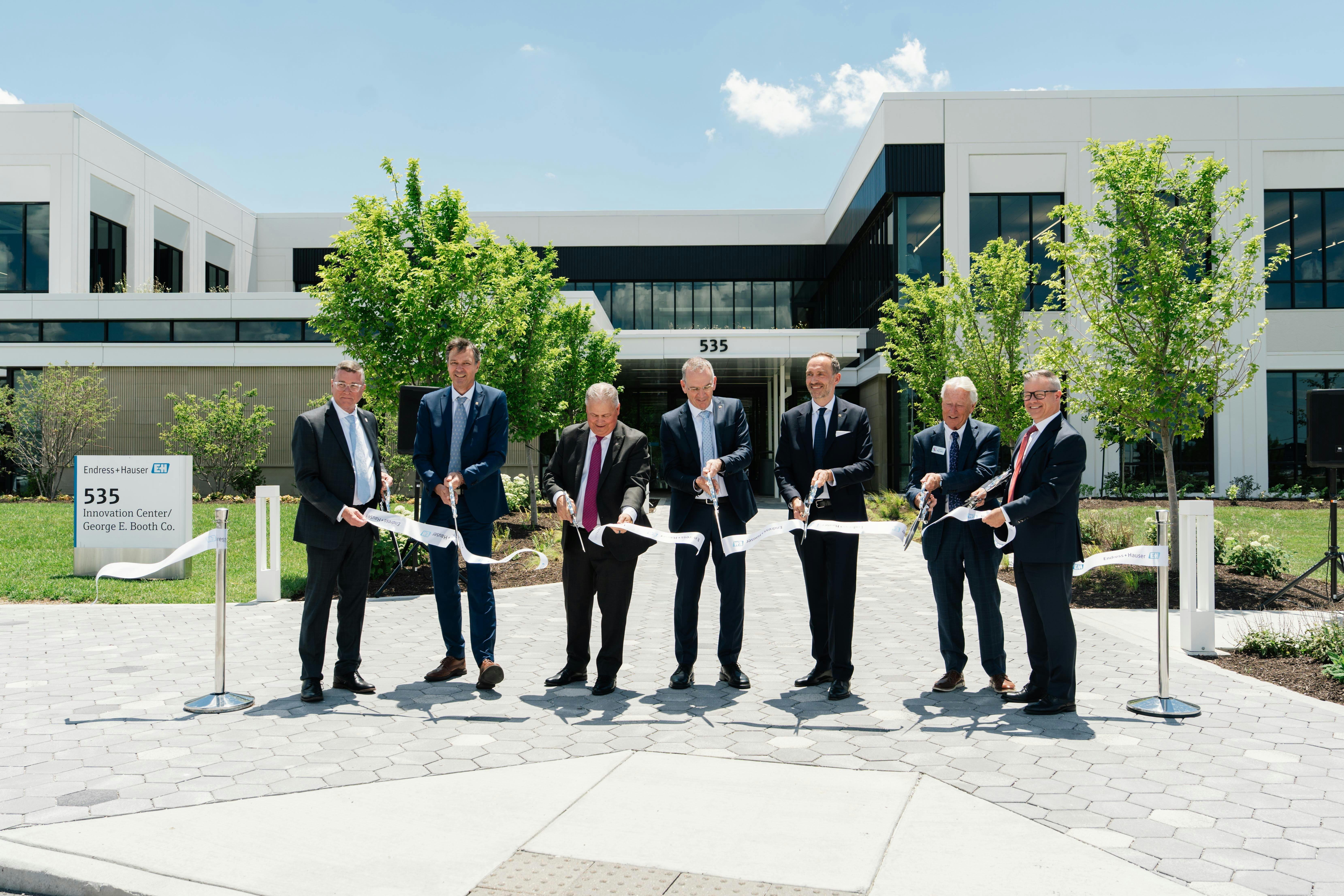 Wielding the traditional, big, shiny scissors, ribbon cutters inaugurating Endress+Hauser USA Innovation Center and new George E. Booth headquarters on June 23 include (l. to r.) Mark Myers, mayor of Greenwood, Ind., Laurent Malley, chief sales officer at Endress+Hauser, Todd Lucey, managing director at Endress+Hauser USA, Peter Selders, CEO at Endress+Hauser, Steven Endress, president of Endress+Hauser&rsquo;s Supervisory Board, George E. Booth II, and Scott Young, president of George E. Booth.