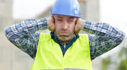 Construction worker holding his hands over his ears, suffering from noise pollution on building site