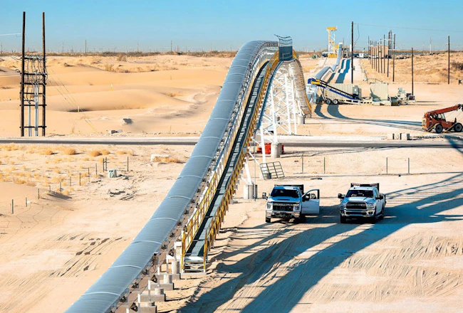 Two pickup trucks parked next to Sew-Eurodrive&rsquo;s Dune Express conveyor system in West Texas&rsquo; Permian Basin.