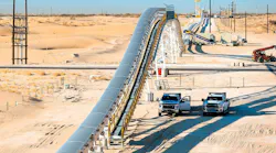 Two pickup trucks parked next to Sew-Eurodrive’s Dune Express conveyor system in West Texas’ Permian Basin.