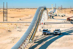 Two pickup trucks parked next to Sew-Eurodrive’s Dune Express conveyor system in West Texas’ Permian Basin.