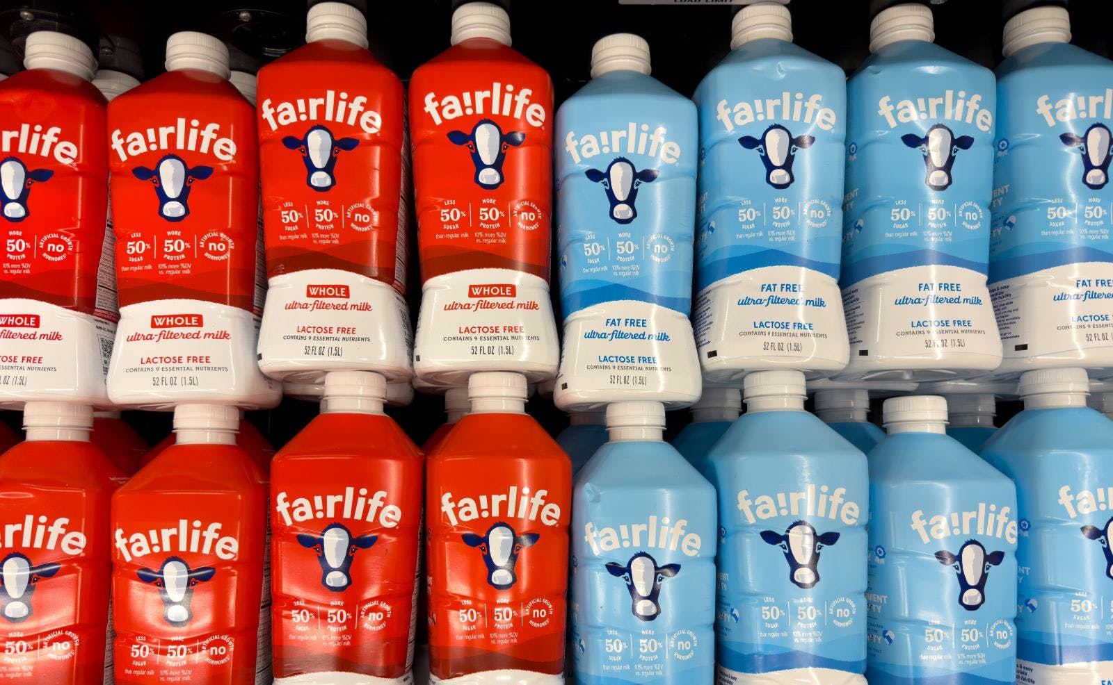 Fairlife milk bottles in red and blue packaging in store refrigerator.