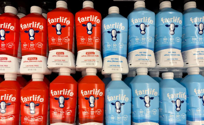 Fairlife milk bottles in red and blue packaging in store refrigerator.