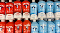 Fairlife milk bottles in red and blue packaging in store refrigerator.