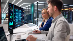 Two specialists oversee real-time server inference operations in data center environment using laptops.