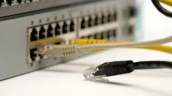 Close-up of a disconnected Ethernet cable lying near active ports of a network switch, symbolizing internet failure, IT troubleshooting, and connectivity issues.