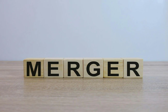 The word 'MERGER' spelled out on wooden blocks on a wooden surface