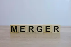 The word 'MERGER' spelled out on wooden blocks on a wooden surface