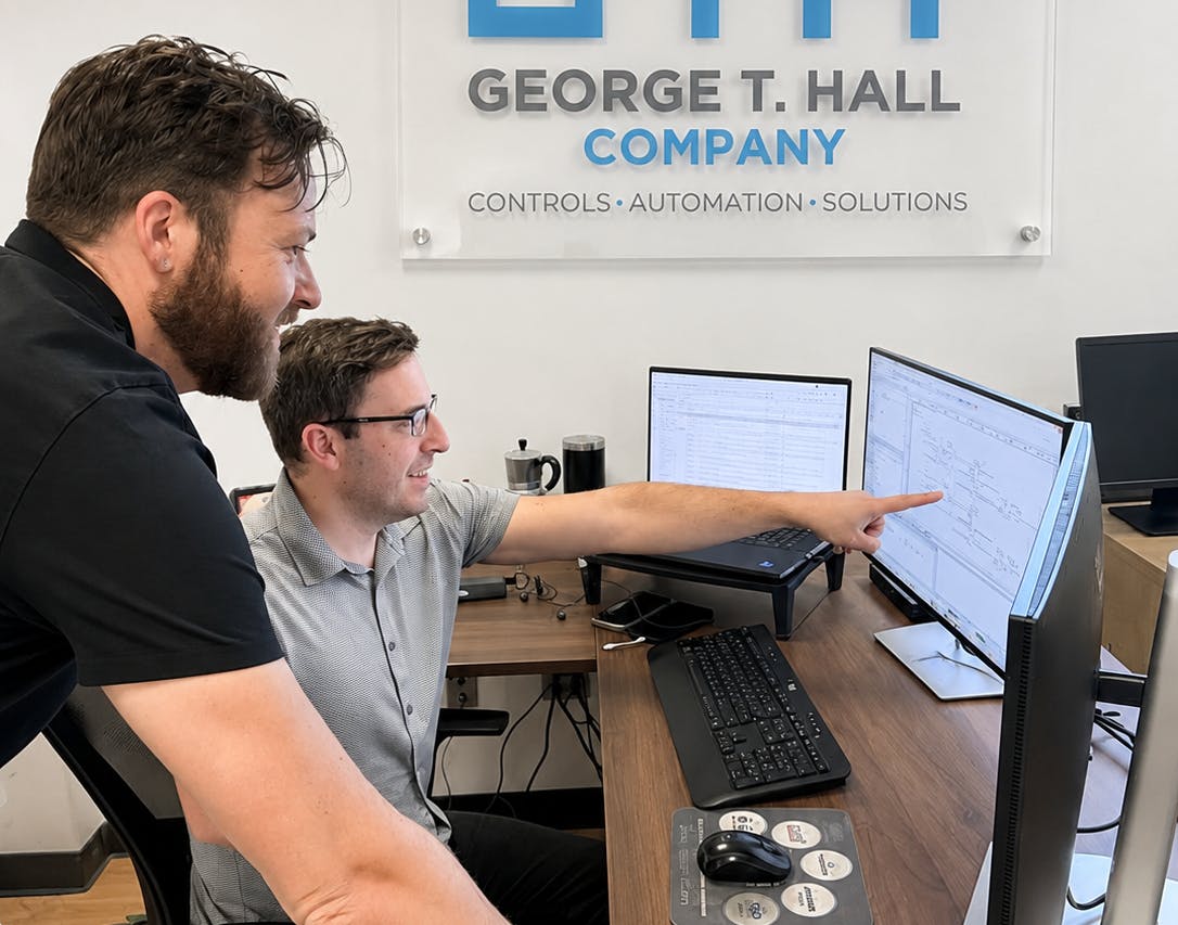Dylan Lane, digital manufacturing systems manager (standing), and Gotzon Mugica, lead control systems engineer III (seated), review code for an upcoming project at George T. Hall, a system integrator in Anaheim, Calif.