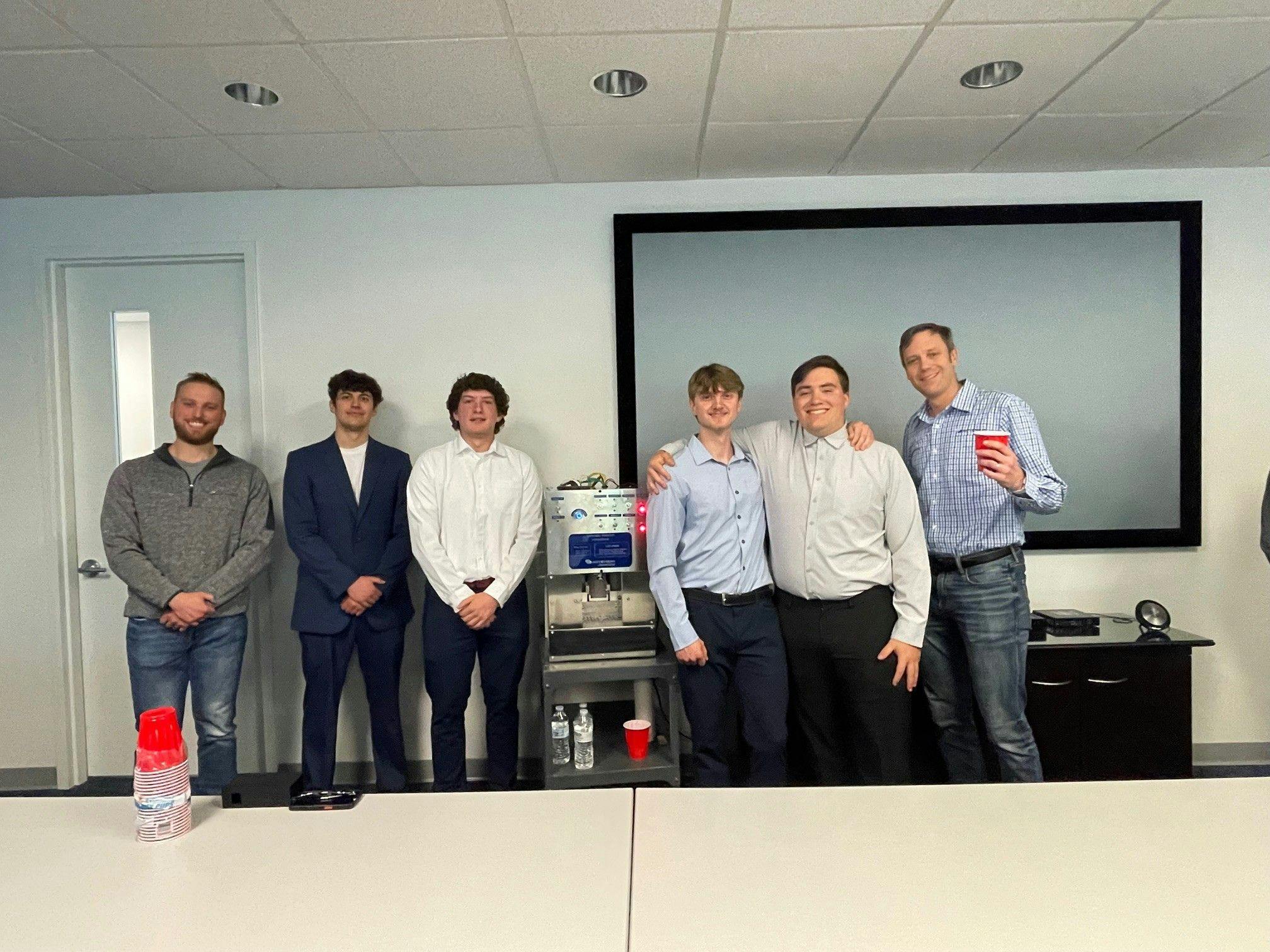 Figure 3: Nick Francone (far left), senior engineer, and Brian Fenn (far right), COO at Actemium-Avanceon, congratulate Penn State Berks students during their senior capstone project presentation of Bartendo. The students presented their engineering approach, design process and final system demonstration to the company&rsquo;s team members.
