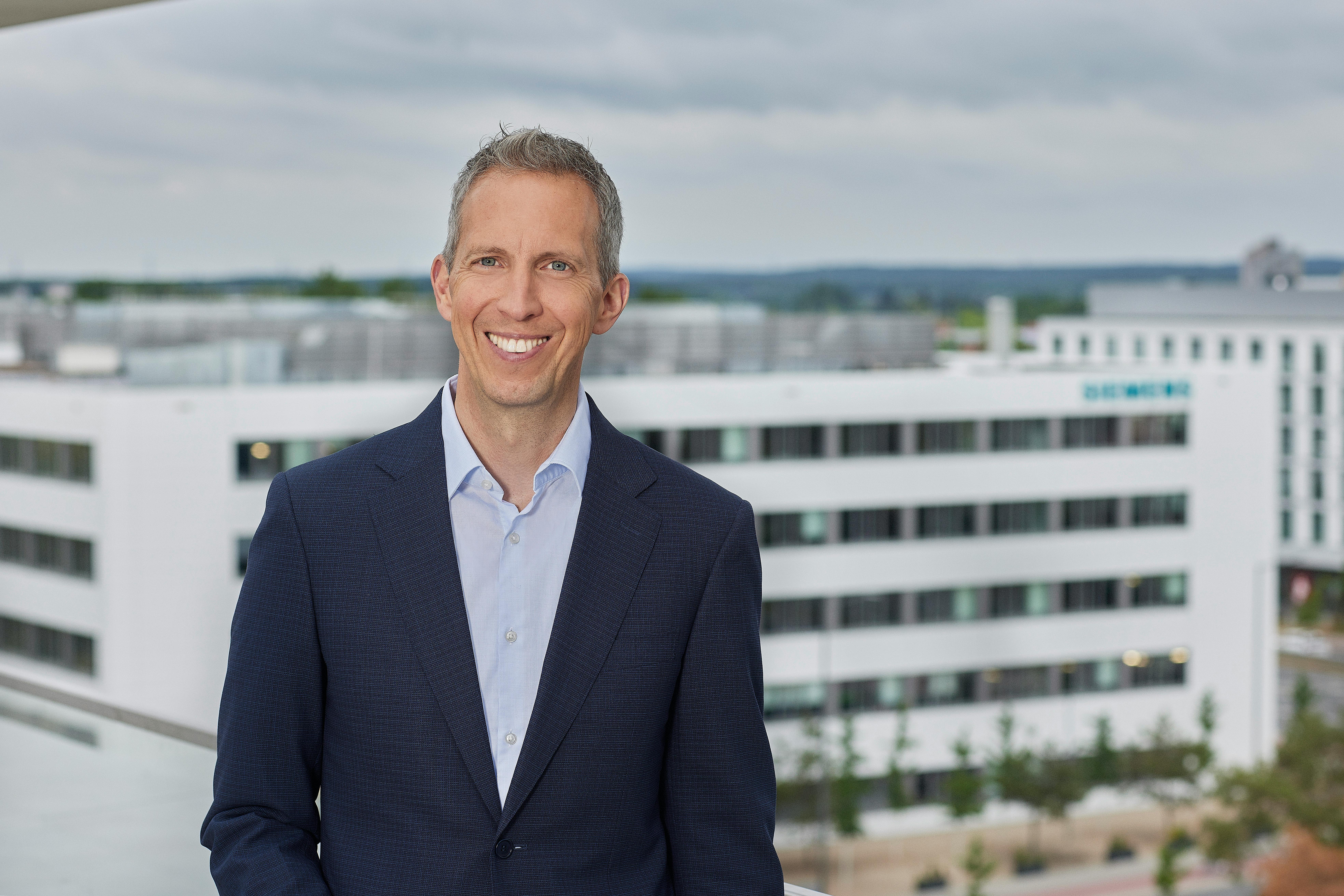 Rainer Brehm headshot in front of a skyline