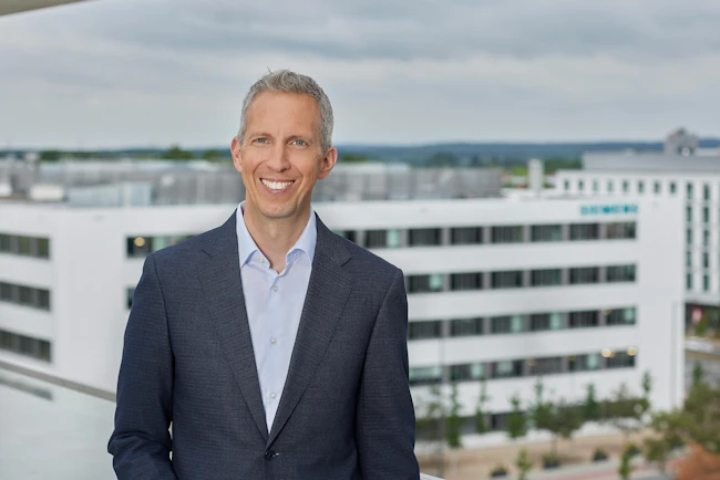 Rainer Brehm headshot in front of a skyline
