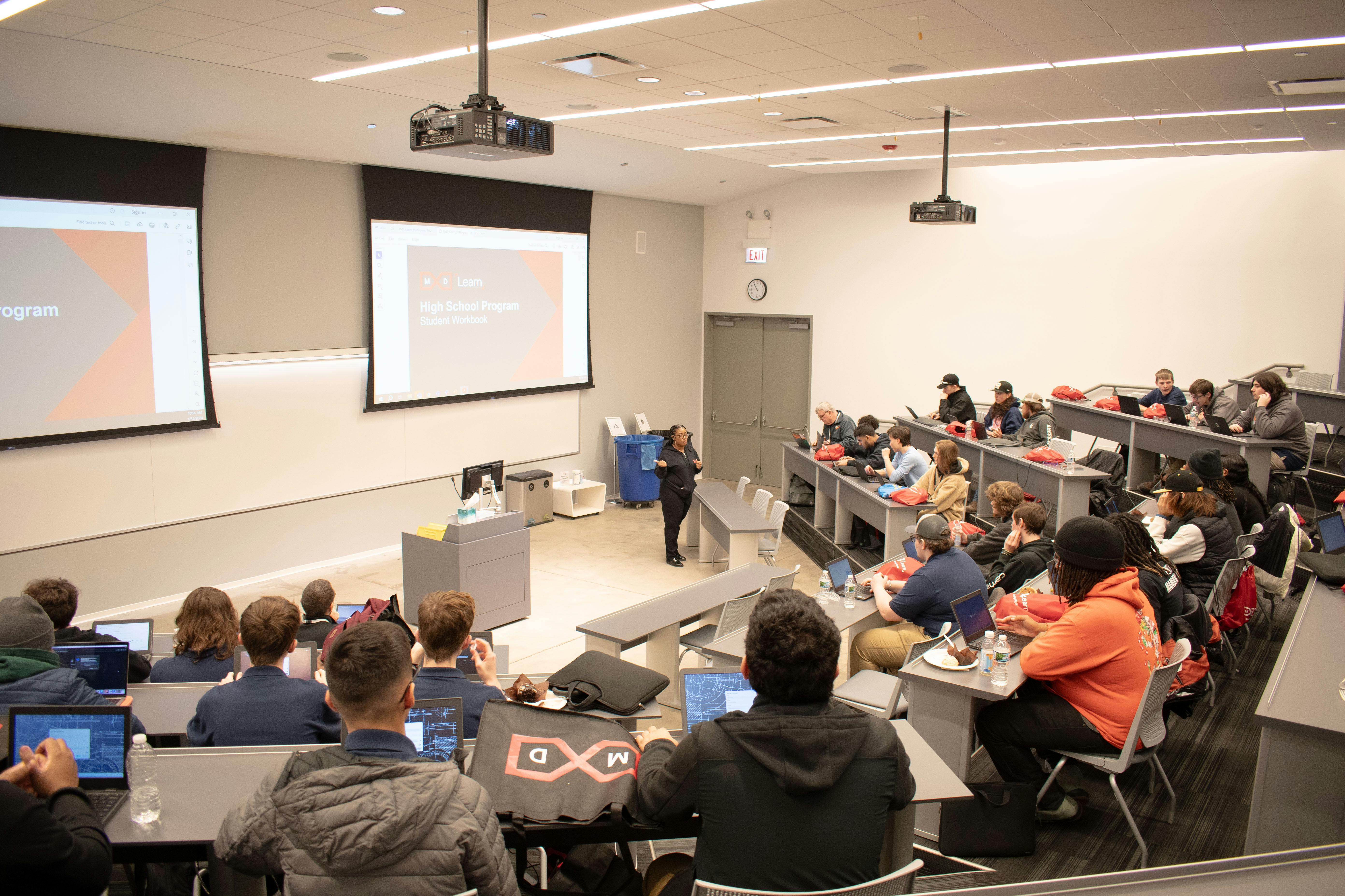 Figure 1: Visiting students attend a classroom demonstration at MxD in Chicago, which works to strengthen U.S. manufacturing by advancing technology adoption, cyber readiness and building a strong workforce.