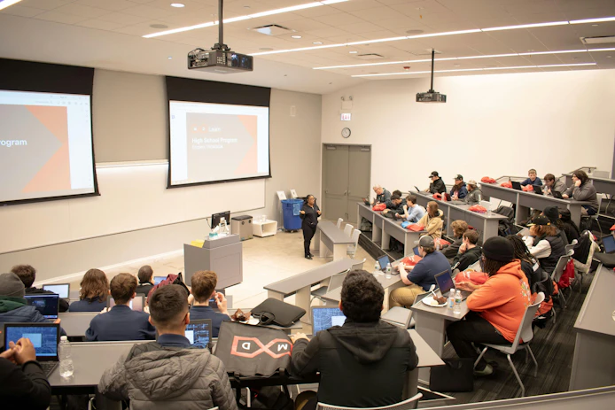 Figure 1: Visiting students attend a classroom demonstration at MxD in Chicago, which works to strengthen U.S. manufacturing by advancing technology adoption, cyber readiness and building a strong workforce.