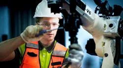 An engineer programs or repairs a high-tech industrial robot. This smart factory uses AI-driven automation for advanced manufacturing or microchip production.